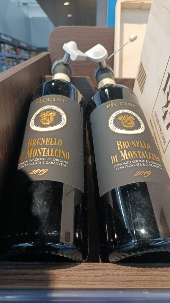 Garrafa de vinho tinto Piccini Brunelo DOCG com seu icônico rótulo preto e dourado.